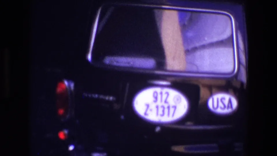 Tight home-movie frame of the black car rear in Ireland, with plate 912 Z-1317 and a visible USA sticker.