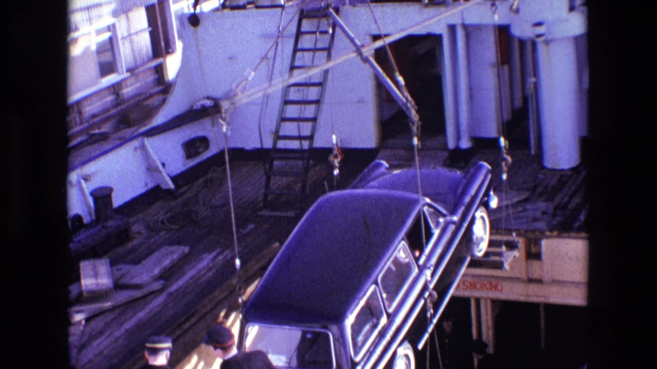 The black vehicle is suspended above the deck as ship fittings, ladders, and rigging fill the background.