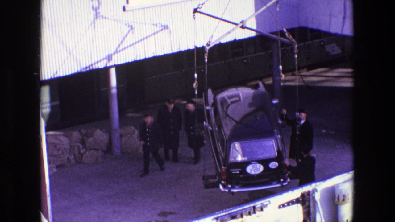 1969 Ireland dockside footage shows a black hearse being lifted by crane while several men in dark coats stand nearby.