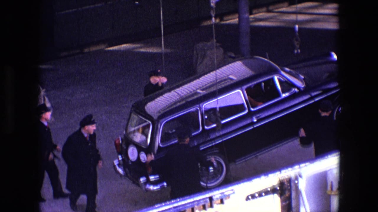 Black estate car suspended near a platform while several men stand around it.