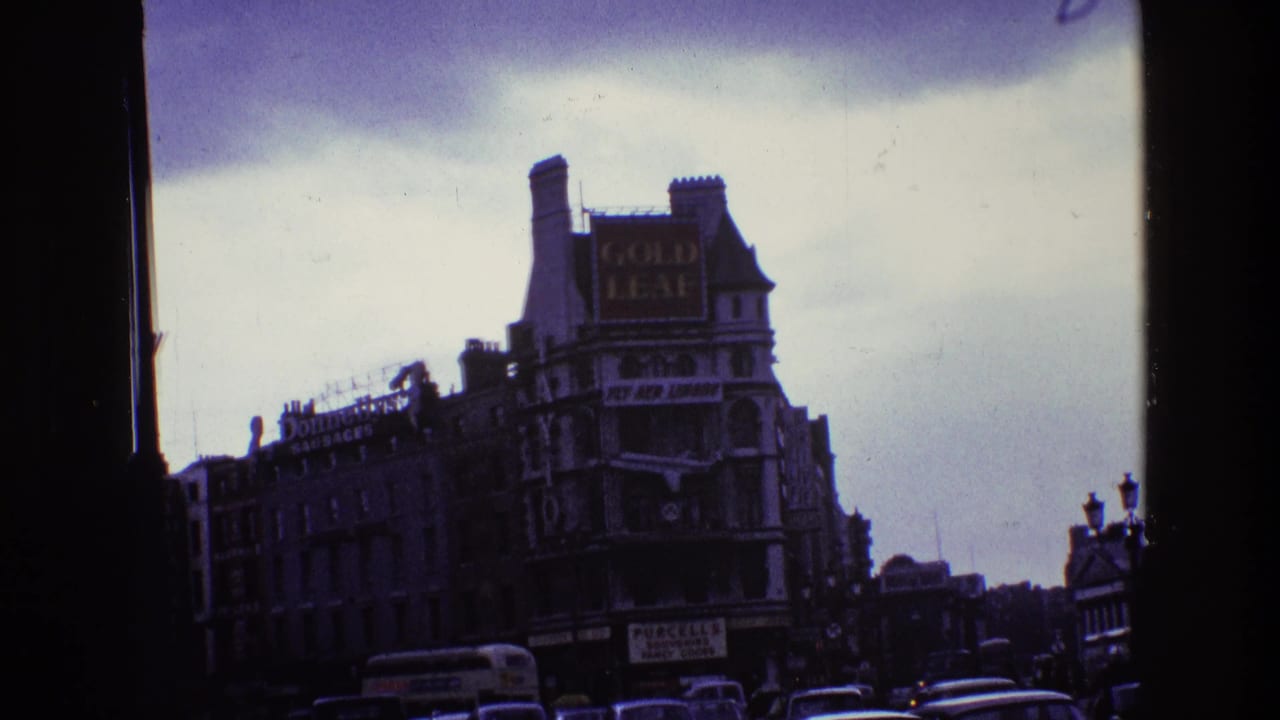 1969 Ireland street view with older buildings, a large Gold Leaf sign, traffic below, and dark window-frame edges.