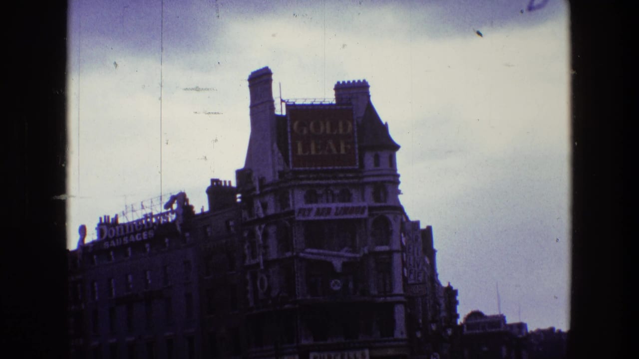 1969 Ireland urban street frame showing the Gold Leaf sign, Donnelly's Sausages lettering, older buildings, and vehicles below.