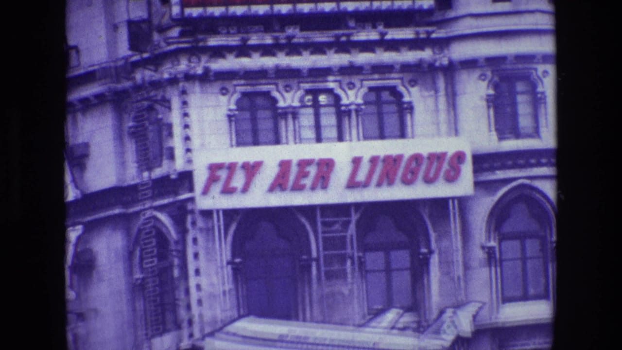 Building facade with a red FLY AER LINGUS sign above a mounted airplane model.