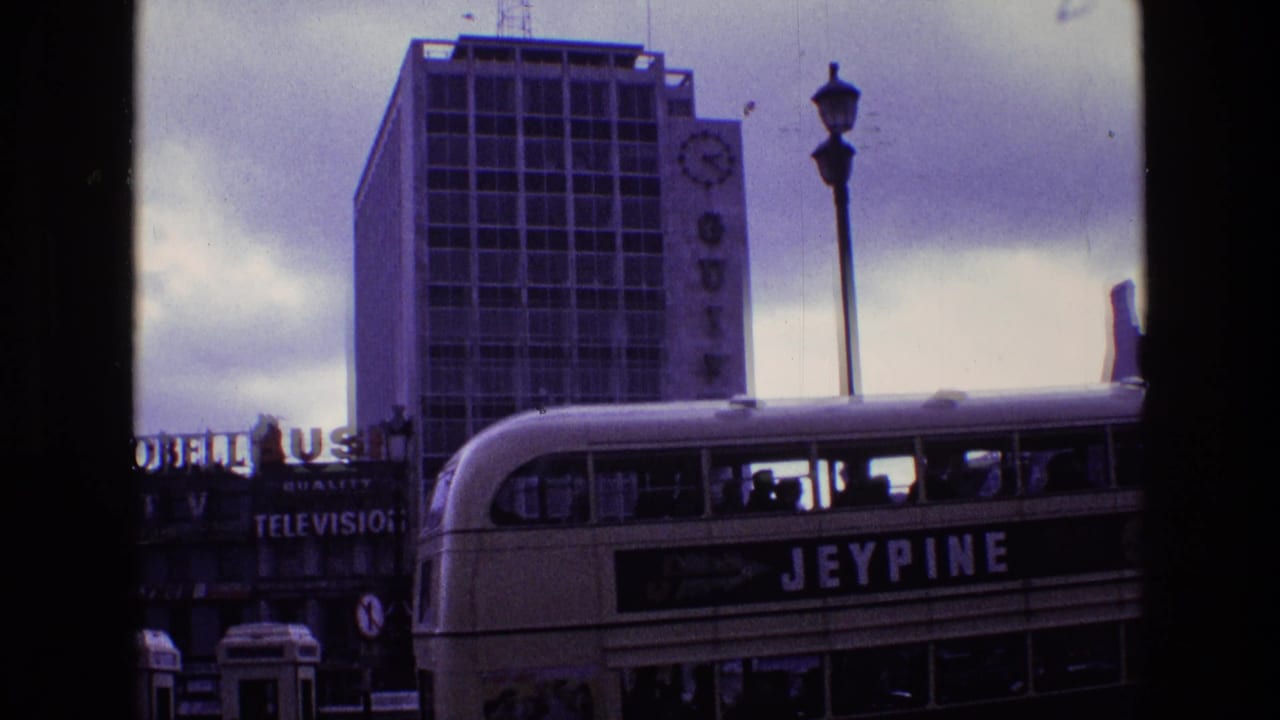 A Jeypine double-decker bus turns through a London street scene with Guinness signage, television sign text, and period street traffic.