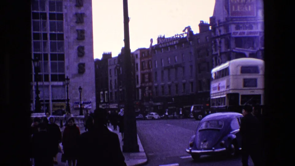 A vintage Volkswagen Beetle, pedestrians, and a double-decker bus share a London street near visible Guinness building signage.