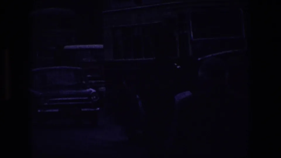 Underexposed end frame from the 8mm clip, showing a large vehicle passing close in a busy 1969 Irish street scene.
