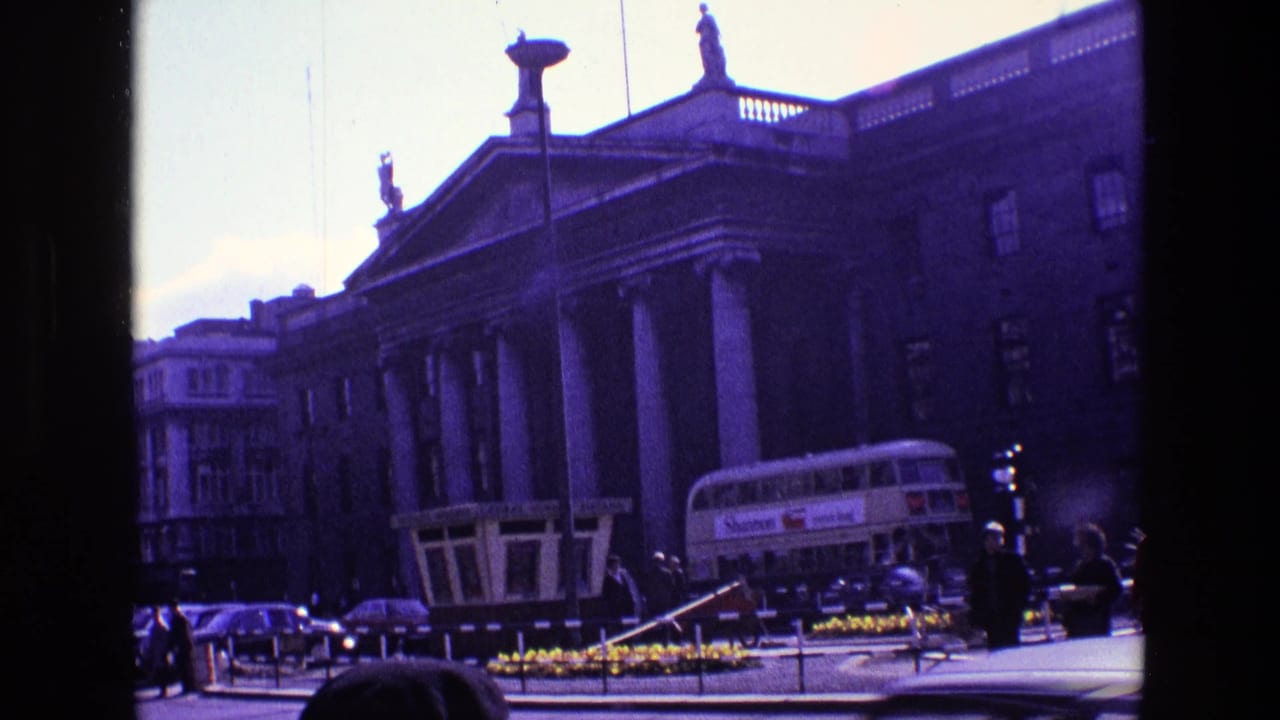 Columned building beside traffic with a double-decker bus in view.