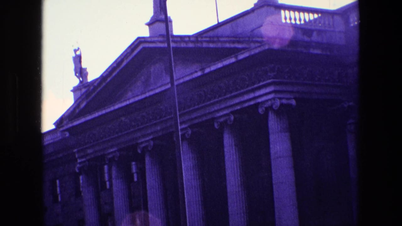 Columned building with triangular pediment and rooftop statue.