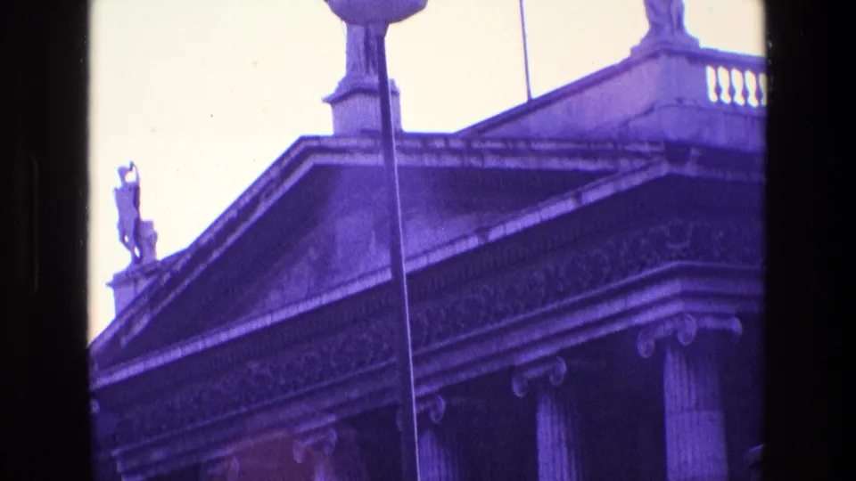 1969 Ireland home-movie frame showing the upper facade of a neoclassical public building with statues and columns.