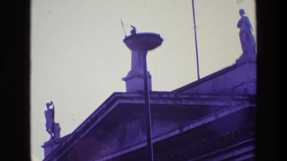 Final 1969 Ireland frame with rooftop statues, flagpoles, balustrade, and the upper edge of a neoclassical building.