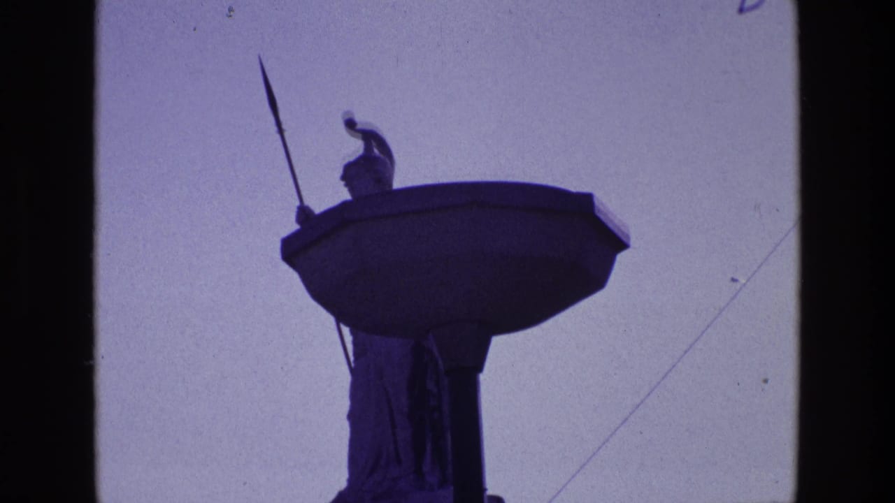 1969 Ireland 8mm frame showing a silhouetted rooftop statue or monument element against bright sky, with dark film edges.