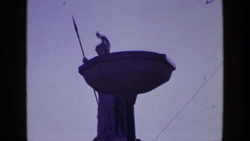 1969 Ireland 8mm frame showing a silhouetted rooftop statue or monument element against bright sky, with dark film edges.