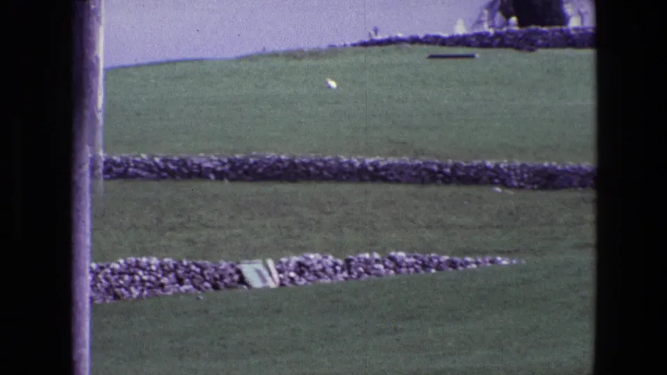 1969 Ireland countryside frame with rolling grass, dry stone walls, a distant white sheep, and saturated 8mm color.