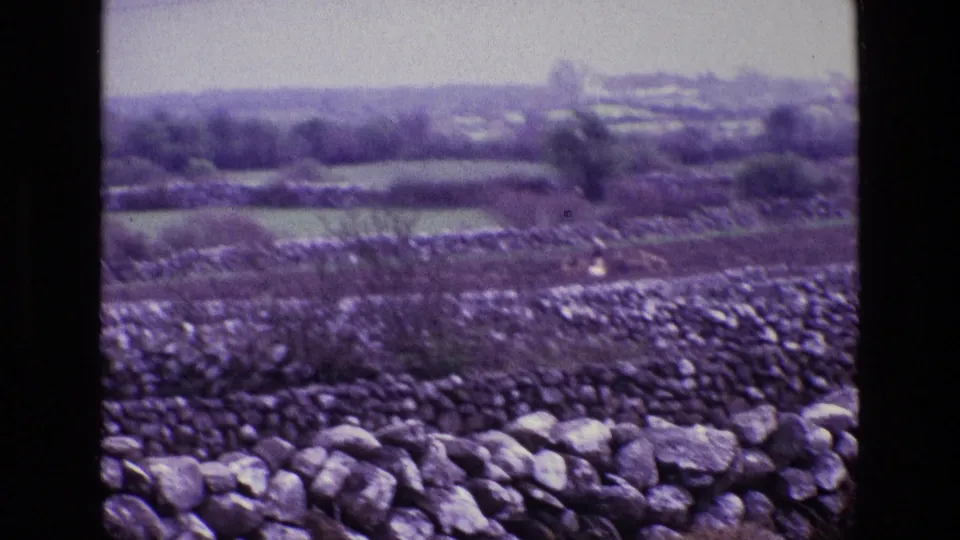 1969 Ireland home-movie view of stone-walled fields and a distant rural valley landscape.