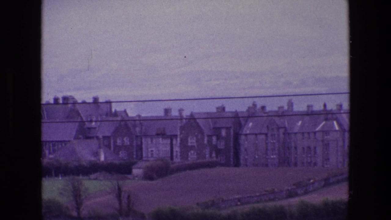 A distant 1969 Ireland countryside view with stone or brick houses above open pasture and overhead utility lines.