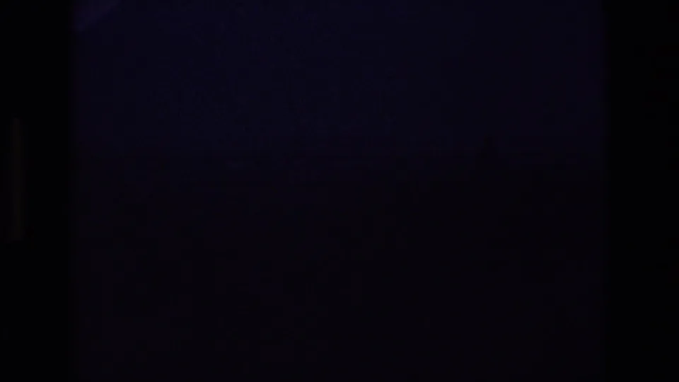 Mostly dark 8mm frame at the start of the clip, with no clear subject visible yet.