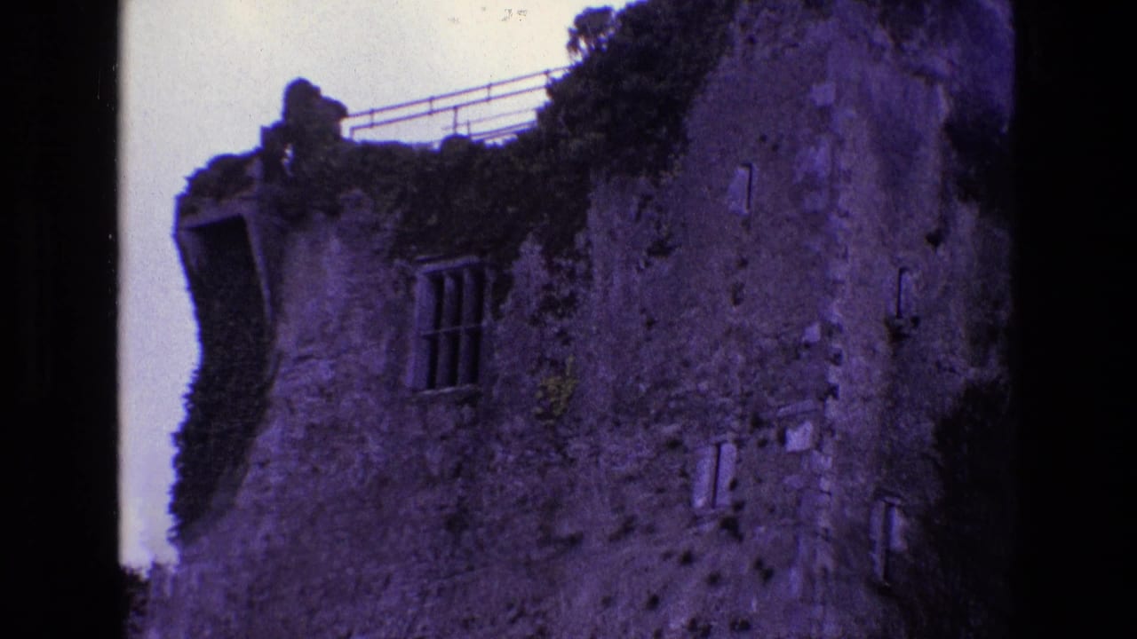 Weathered stone ruin with barred window, ivy, roof railing, and black 8mm film borders.