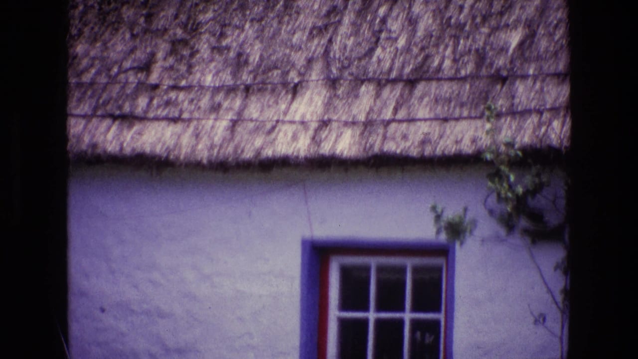 1969 Ireland 8mm frame showing a whitewashed cottage wall, thatched roof edge, and blue-and-red trimmed window.