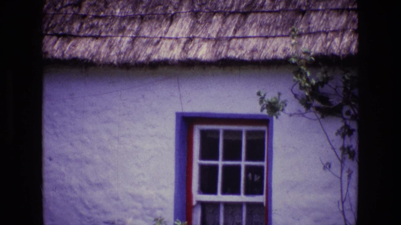 1969 Ireland frame with a close cottage facade, showing a thatched roof, painted window frame, and vines at the right edge.