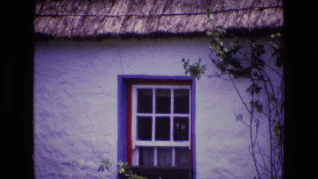 1969 Ireland 8mm frame showing a whitewashed thatched cottage exterior with a blue window frame, red trim, and climbing vines.