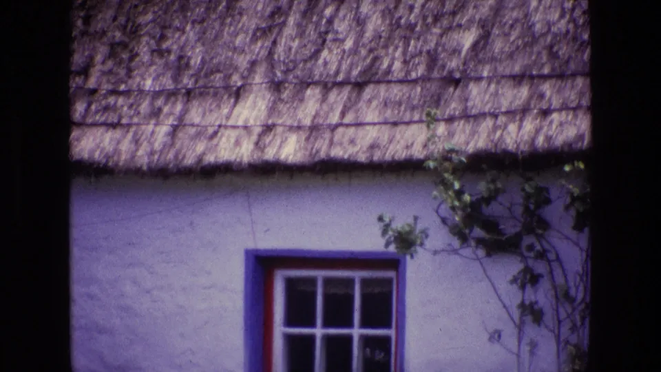 1969 Ireland 8mm frame with the cottage window lower in view beneath a textured thatched roof and vine-covered wall edge.