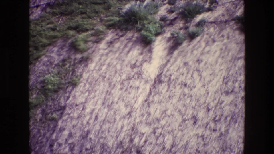 1969 Ireland 8mm frame showing a pale, steep rocky hillside with scattered green growth and dark film borders.