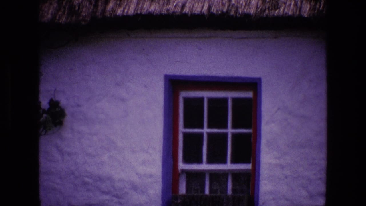 1969 Ireland 8mm frame showing a whitewashed thatched cottage wall with a red and blue framed window.