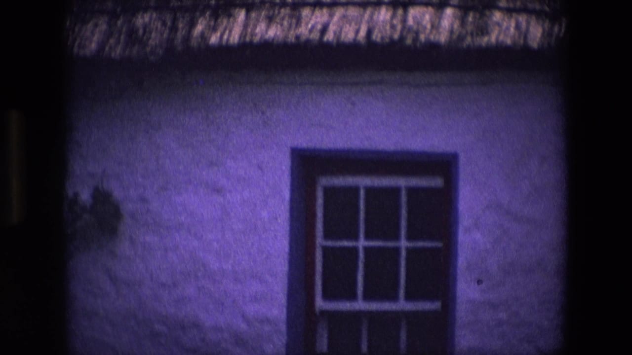 1969 Ireland home-movie frame of a whitewashed cottage window under thatch, with visible 8mm color shift.