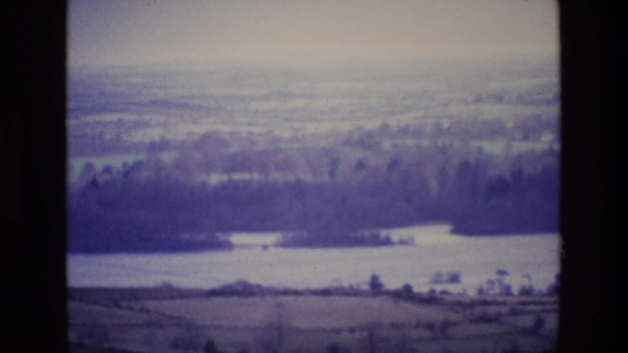 Distant water and tree line across open countryside with soft film blur.