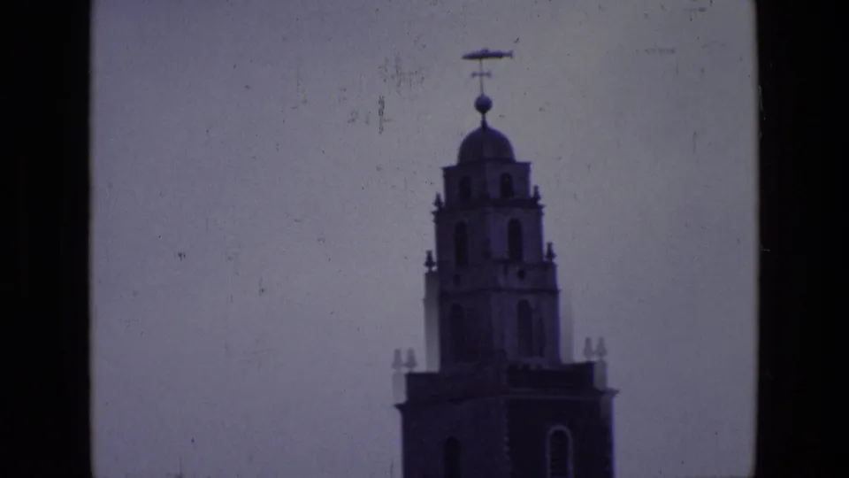 1969 Ireland 8mm frame isolating the upper clock tower, with domed top, weather vane, and soft home-movie exposure.