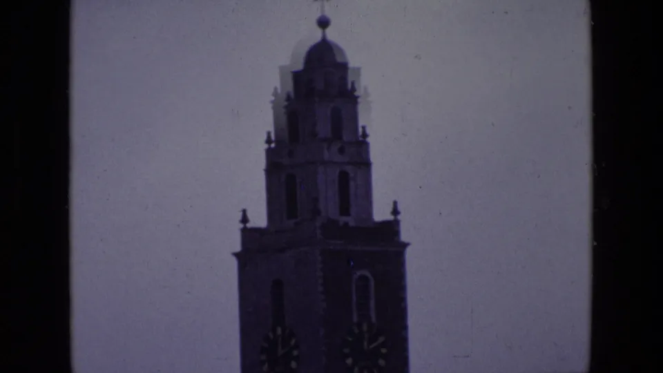 1969 Ireland 8mm frame with the clock tower centered against a cool, faded sky and visible film grain.