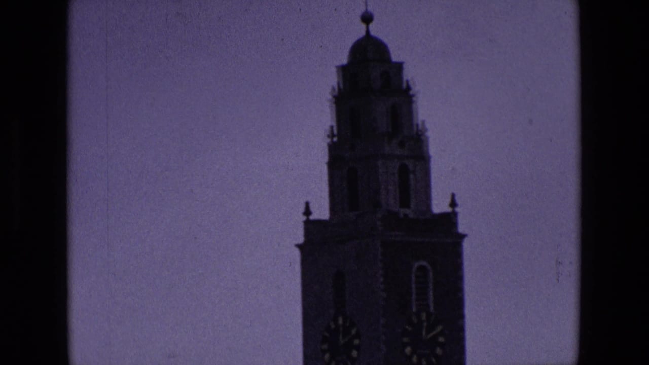 Silhouetted historic tower with visible clock faces against a purple dusk sky.