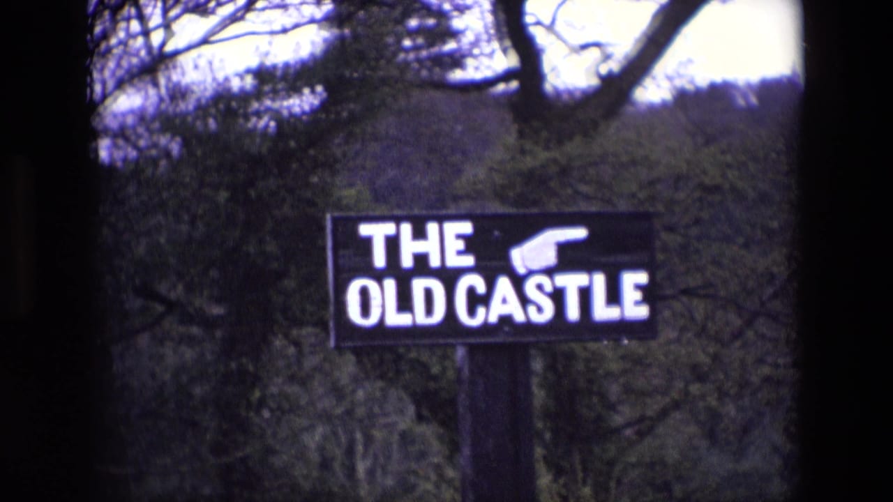 Black sign reading THE OLD CASTLE with a pointing hand, set among trees.