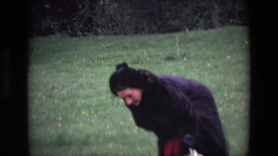 A closer 8mm frame shows the woman smiling while bent forward in the grassy Irish field.