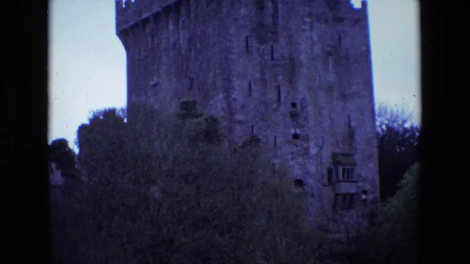 1969 Ireland 8mm frame with a closer exterior view of the castle wall, crenellations, narrow openings, and trees below.
