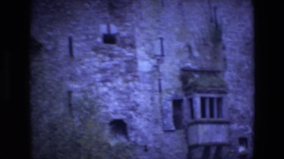 1969 Ireland 8mm frame showing a soft close exterior of stonework, small wall openings, and a projecting balcony window.