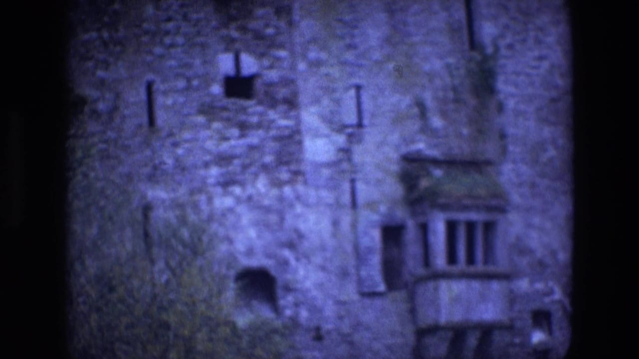 Weathered stone castle wall with narrow openings and a small projecting balcony.
