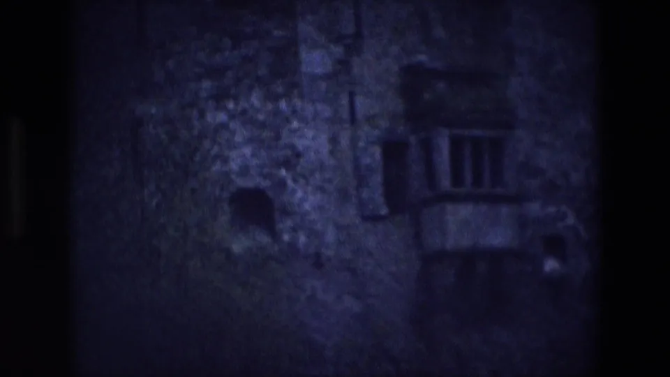 1969 Ireland 8mm frame showing a dim stone castle exterior with small openings and a balcony-like projection.