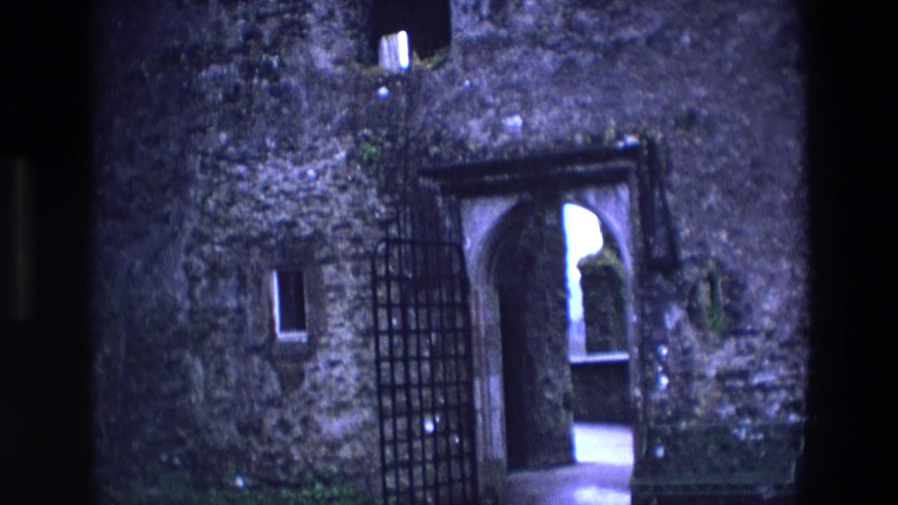 1969 Ireland 8mm frame showing an open iron gate and arched stone doorway in a castle exterior.