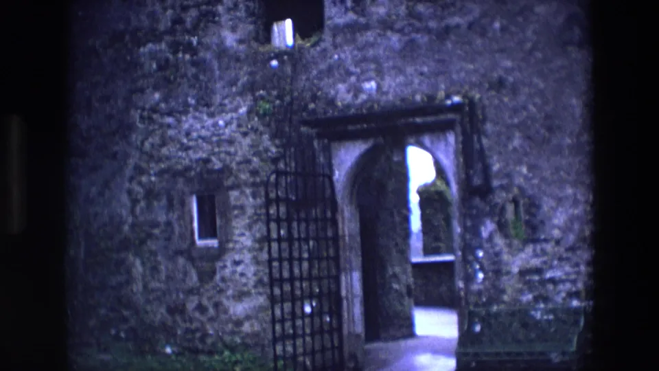 1969 Ireland 8mm frame with a close visitor view of the castle gate, arched entry, and weathered stone.