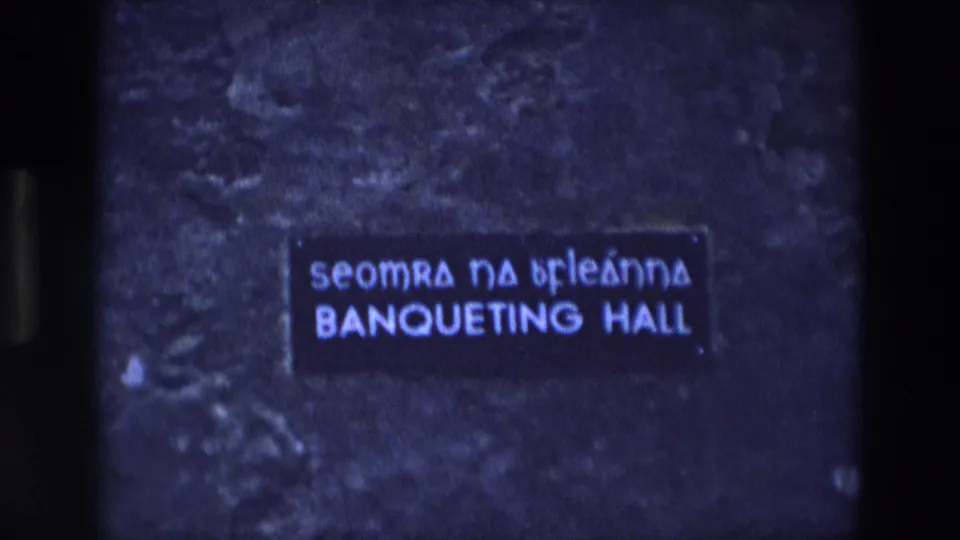 1969 Ireland 8mm frame with a rectangular Irish-English banqueting hall sign in blue-toned archival footage.