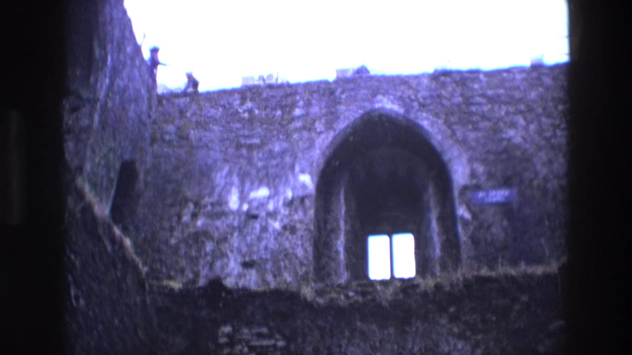 Dim stone castle interior with an arched recess and two narrow bright windows.