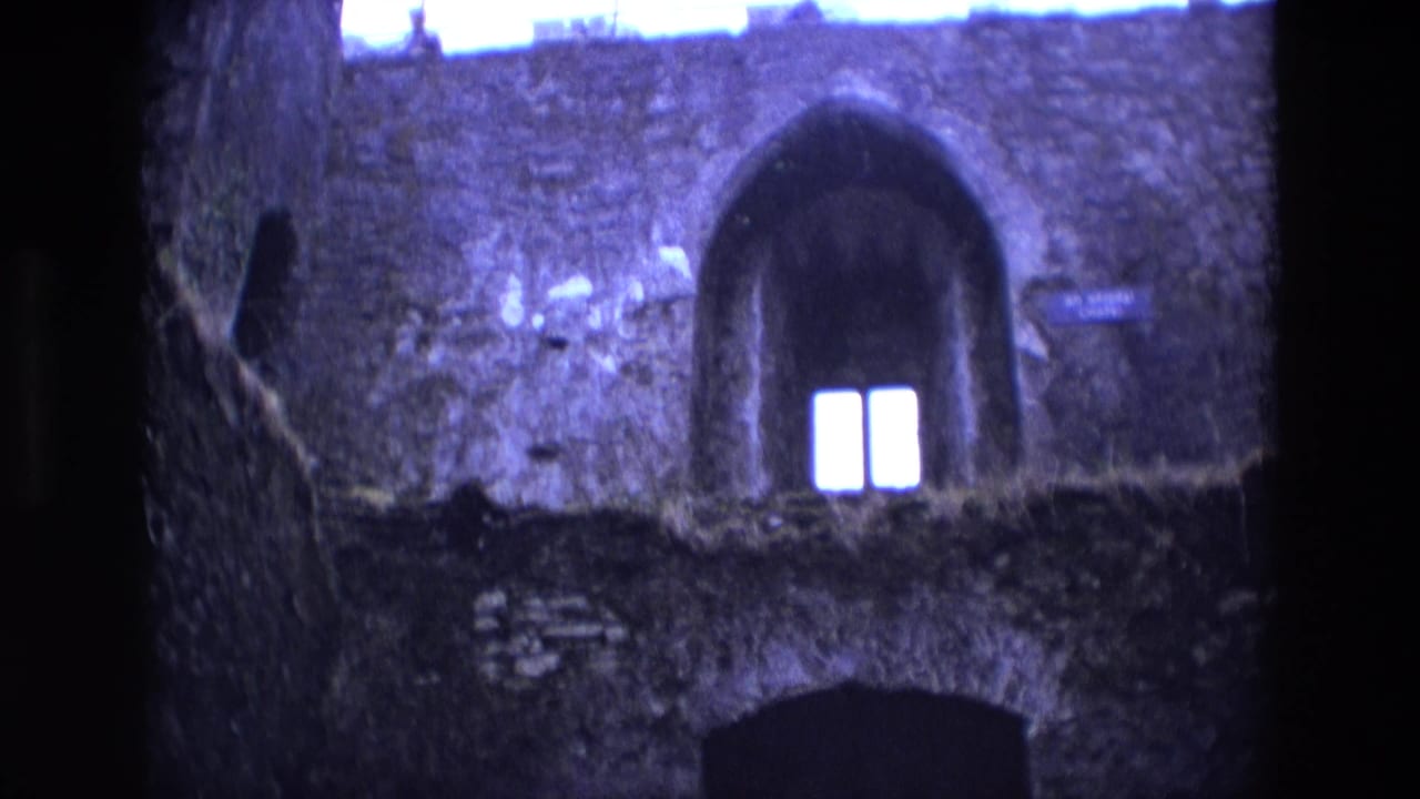 Stone castle wall with arched window recess and shadowed lower doorway.