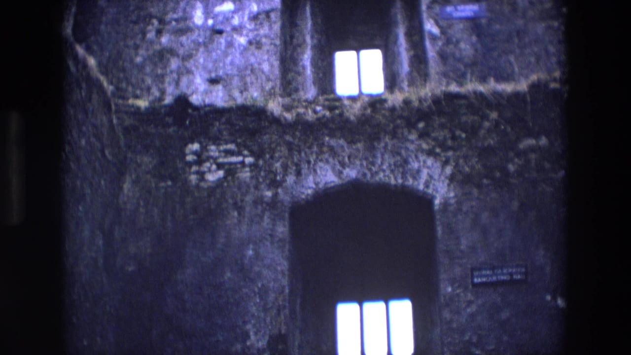 1969 Ireland 8mm frame showing rough chapel masonry, glowing window panes, and a dark arched opening.