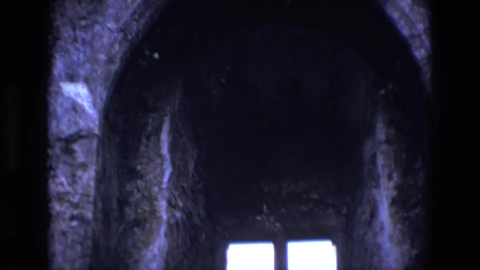 1969 Ireland 8mm view into a shadowed chapel archway with bright window panes below.