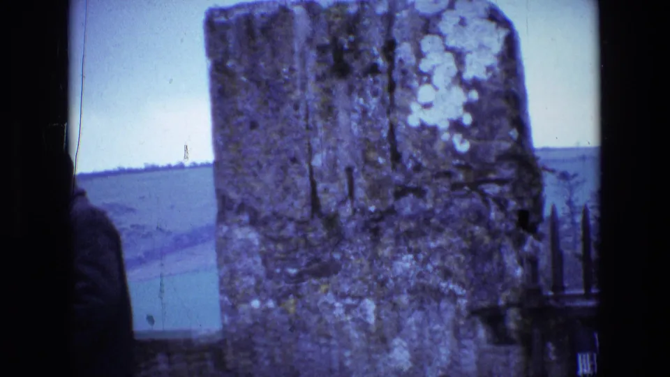 1969 Ireland travel frame with rough stone posts in the foreground and a distant pale landscape visible beyond the wall.