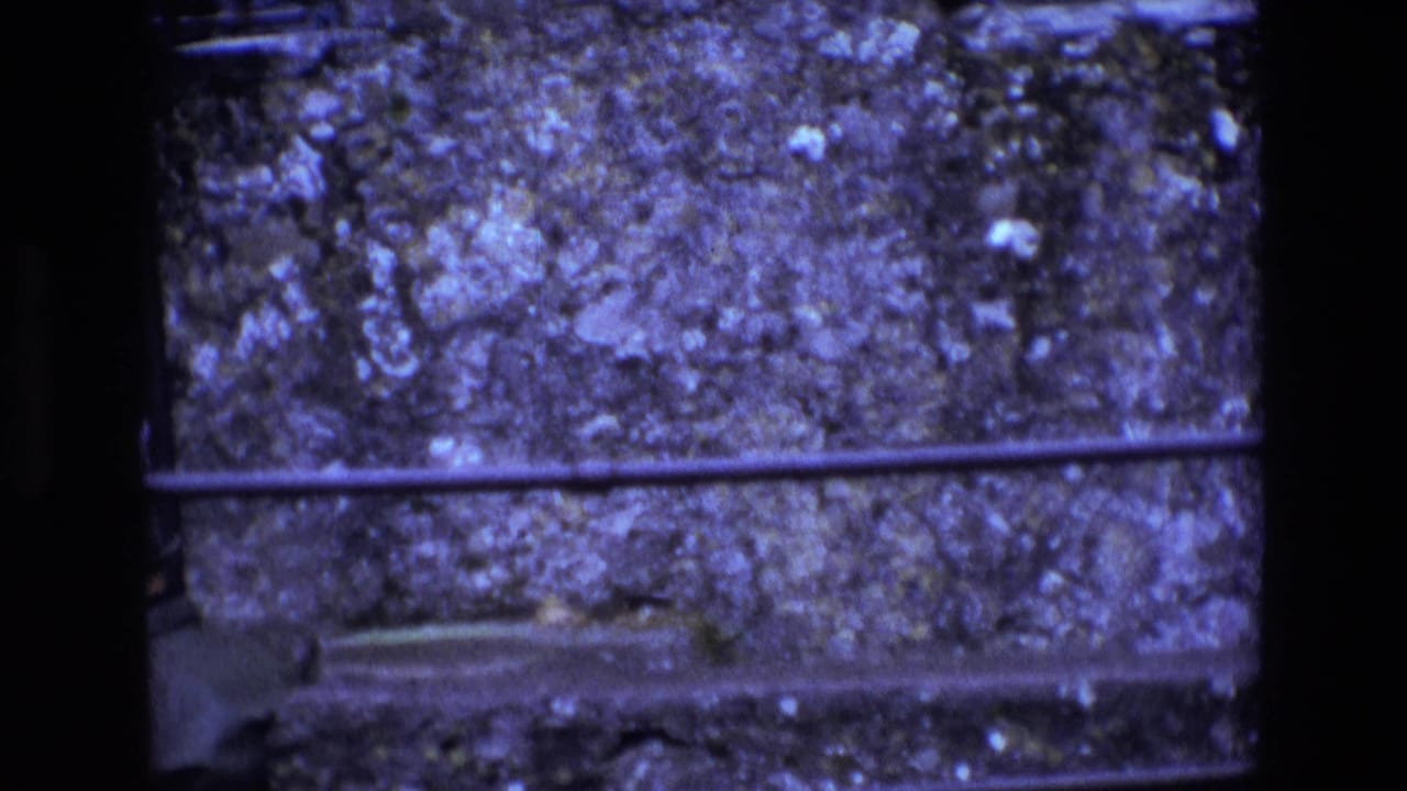 Close view of rough stone wall and horizontal iron bars through a window opening.