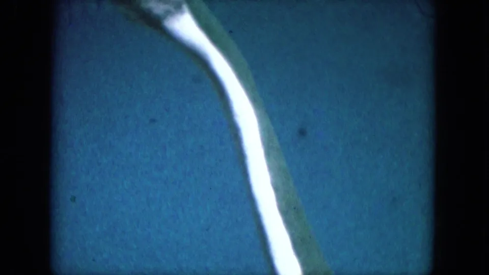 1969 8mm Lake Canyon frame showing the green-and-white form near the right side of a blue field.