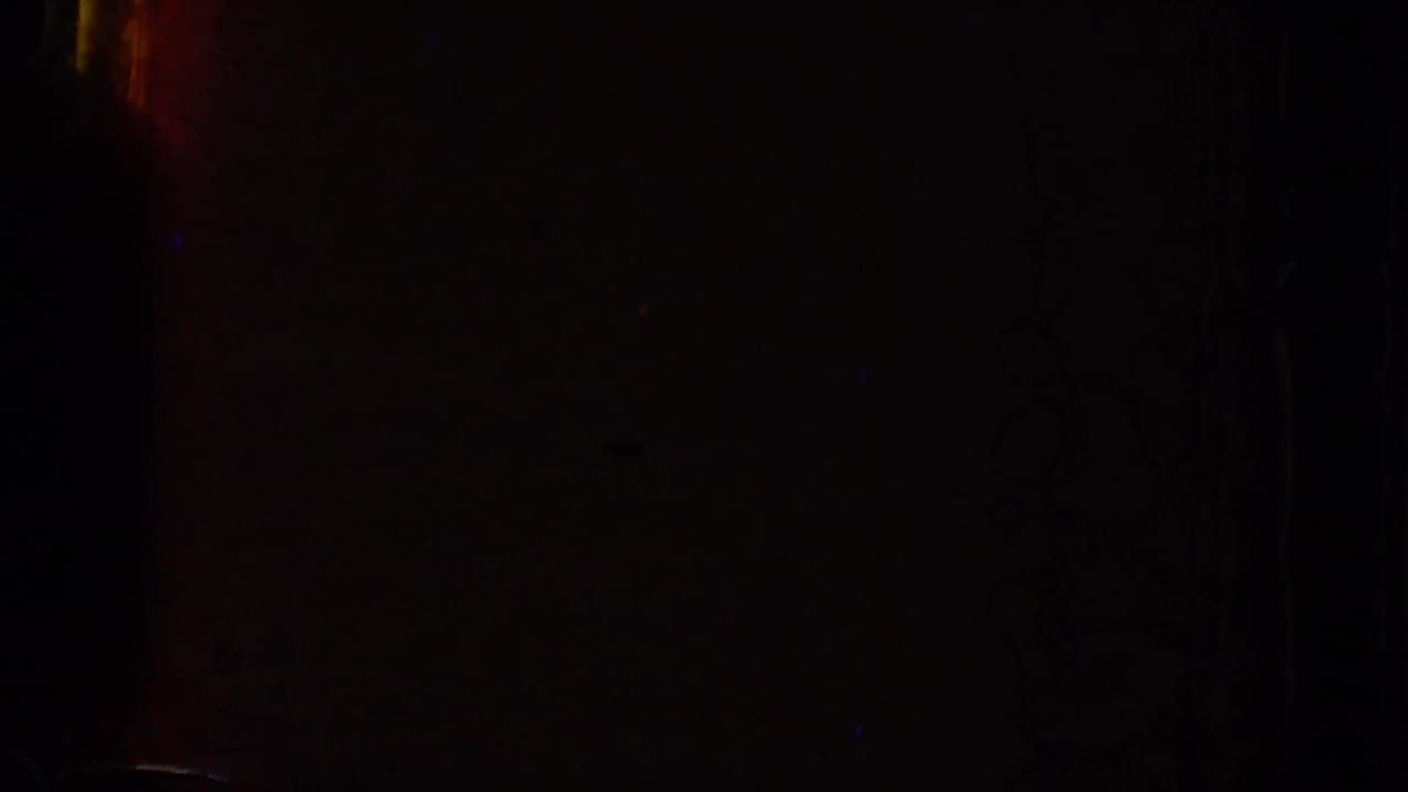 Mostly dark frame with faint reddish and blue film exposure marks.