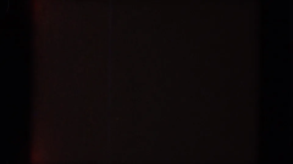 Near-black 8mm frame with reddish shadowing and visible grain within the Lake Canyon clip sequence.